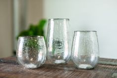 three clear glass vases sitting on top of a wooden table next to each other