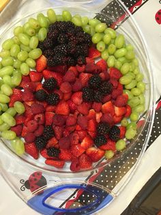 a bowl filled with berries and grapes on top of a table