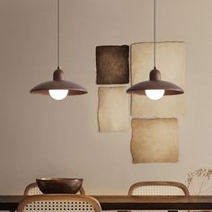 three pendant lights hang above a dining room table with two chairs and a bowl on it