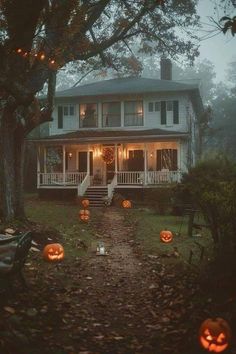 a house decorated for halloween with pumpkins on the ground