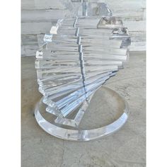 a clear glass sculpture sitting on top of a metal stand in front of a white wall