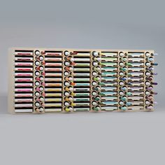 an assortment of pens and pencils are lined up in a row on a gray background