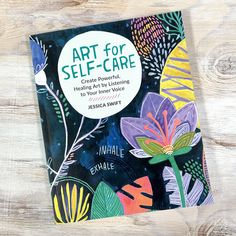 the book art for self - care is sitting on a wooden surface