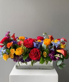 a white vase filled with lots of colorful flowers