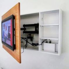 a tv mounted to the side of a white wall next to a wooden framed object