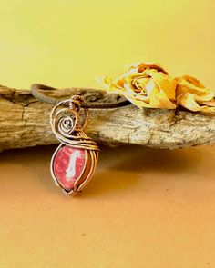 a piece of jewelry sitting on top of a wooden branch next to a yellow flower