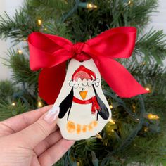 a hand holding an ornament with a penguin on it