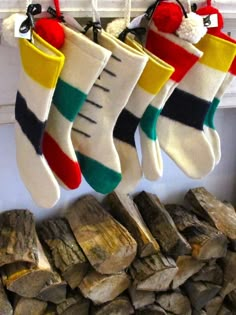 christmas stockings hanging from hooks next to firewood