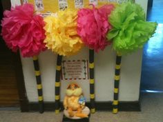 three paper pom poms in front of a bulletin board