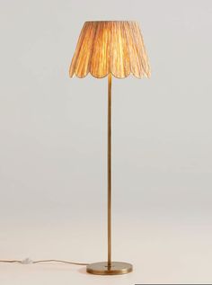 a floor lamp with a beige shade on it's base and a white background