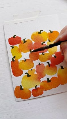 someone is painting an orange and yellow pumpkin pattern on paper with watercolor pencils