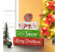 three wooden blocks stacked on top of each other in front of a christmas tree and holiday decorations