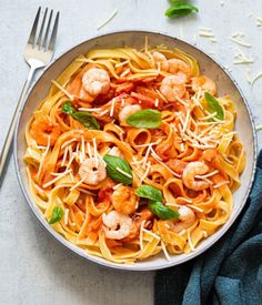 a plate of pasta with shrimp and basil