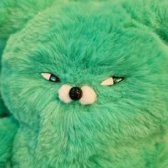 a green teddy bear with eyes wide open