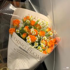 an orange and white bouquet of flowers wrapped in plastic