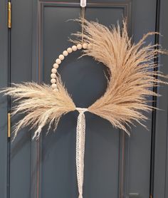 a wreath made out of beads and dried grass hangs on the front door with a beaded tassel