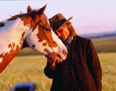 a man standing next to a brown and white horse