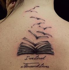 the back of a woman's neck with an open book and birds flying over it