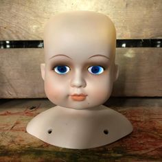 a white mannequin head with blue eyes and an orange lip on it's face