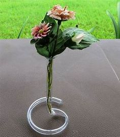 a glass vase with some flowers in it on a table near the grass and trees