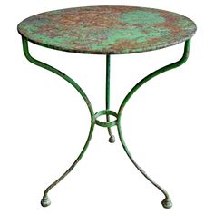 an iron table with green pattered paint on it's top and metal legs