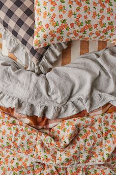 a pile of pillows sitting on top of a bed covered in blankets and ruffles