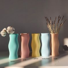 four different colored vases with flowers in them