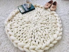 a white knitted round rug with shoes on top