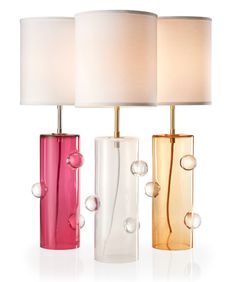 three different colored vases with white lamps on top of them and one has a pink lamp in the middle