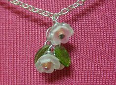 a necklace with white flowers and green leaves