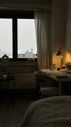 a bedroom with a bed, desk and large window overlooking the city outside at night