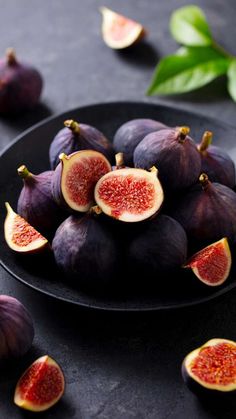 a black plate filled with sliced figs on top of a table