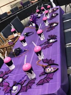 the table is set up with purple and black decorations for an elegant masqueradee party