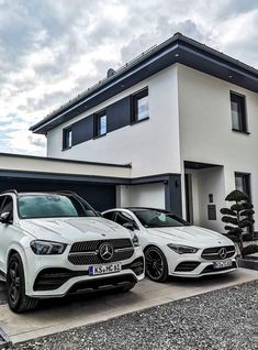 two mercedes benz cars parked in front of a house