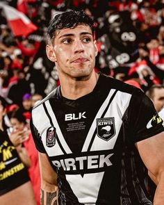 a man standing in front of a crowd wearing a black and white shirt with the words pittek on it