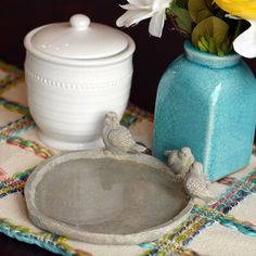 a blue vase with flowers in it sitting on a table next to a white container