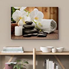 white orchids and black stones on a table with candles in front of the wall