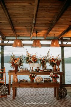 a wooden table topped with lots of flowers next to a wall covered in hanging lights