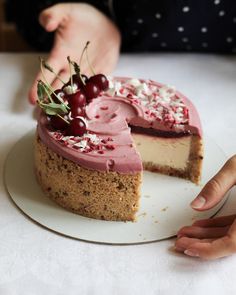 a person is cutting into a cake with cherries on it