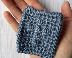 a hand is holding a crocheted square in the palm of someone's hand