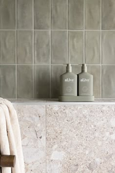 two bottles of soap sitting on top of a counter next to a towel and bath mitt