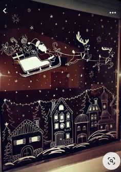 the window is decorated with santa's sleigh and reindeers flying through the night sky