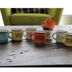 six coffee mugs sitting on top of a wooden table with the words autumn painted on them