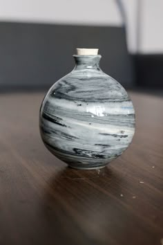 a black and white vase sitting on top of a wooden table