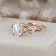 a close up of a ring on a white surface with flowers in the background and a flower