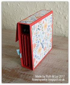 an open red box sitting on top of a wooden table next to a white wall