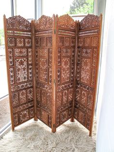 a room divider sitting on top of a white rug in front of a window