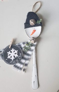 a snowman ornament hanging on a wall with clothes pins attached to it