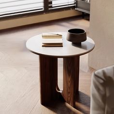 a table with a book, bowl and cup on it in front of a window