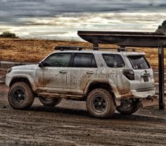 a dirty white truck parked in the dirt